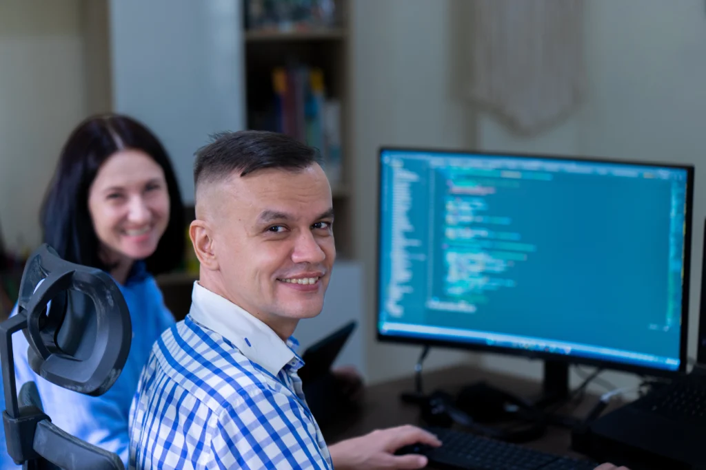 Mila Skriptunova, founder of DevScripty, collaborating with a Senior .NET & Infrastructure Engineer. The background shows professional development tools and a high-load stability architecture setup.