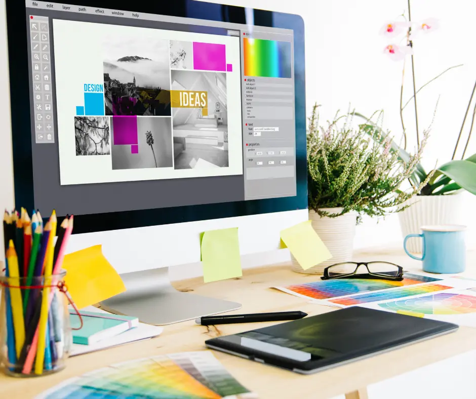 The Designer Handover Trap: Why 1920px Isn't Reality is illustrated by a desktop monitor displaying a design layout on a bright wooden desk cluttered with color swatches, a graphics tablet, and art supplies